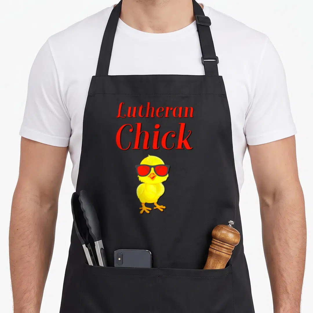 Martin rose apron - Red Lutheran Chick text above a yellow cartoon chick wearing black and red sunglasses — shown on a black cotton canvas apron against a white background