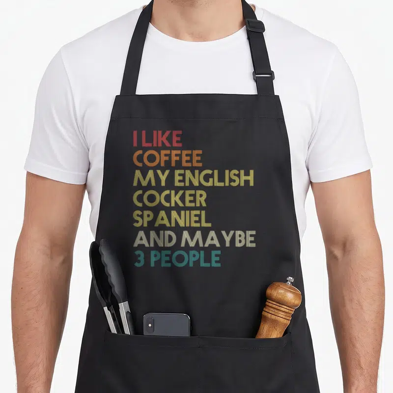 Owner cocker spaniel apron - Stacked striped text reading I like coffee my English Cocker Spaniel and maybe 3 people — shown on a black cotton canvas apron against a white background
