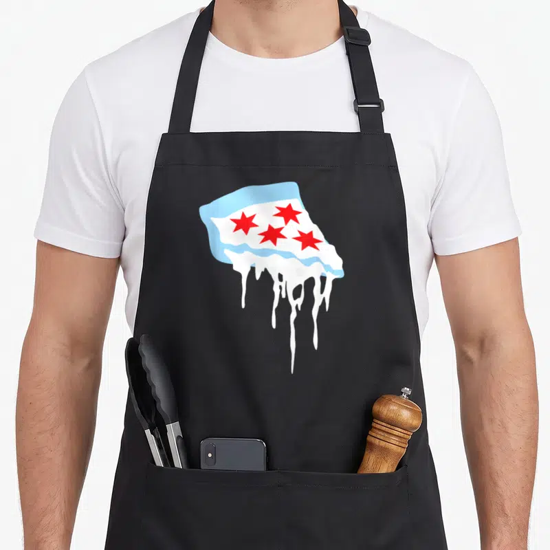 Katie pizza apron - Melting Chicago flag slice with red stars and white drips on blue background — shown on a black cotton canvas apron against a white background