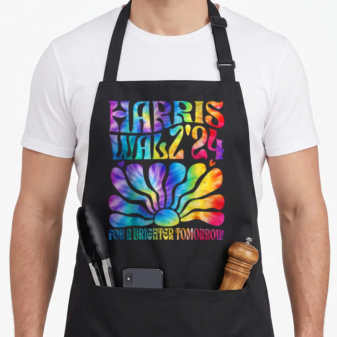 Harris tie dye apron - Stacked HARRIS WALZ 24 text above a tie-dye flower and slogan FOR A BRIGHTER TOMORROW — shown on a black cotton canvas apron against a white background