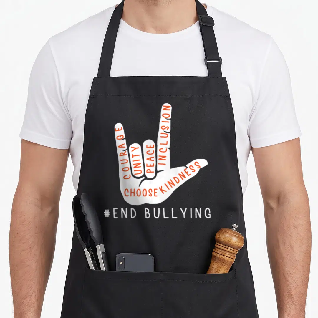 Unity novelty apron - White hand with orange words Courage Unity Peace Inclusion Choose Kindness and white text #End — shown on a black cotton canvas apron against a white background