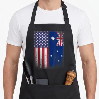 Flag australian apron - Distressed USA and Australian flags side by side in red white blue — shown on a black cotton canvas apron against a white background