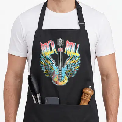 Electric 80s apron - Winged electric guitar with flames and ROCK AND ROLL text in red yellow blue black — shown on a black cotton canvas apron against a white background