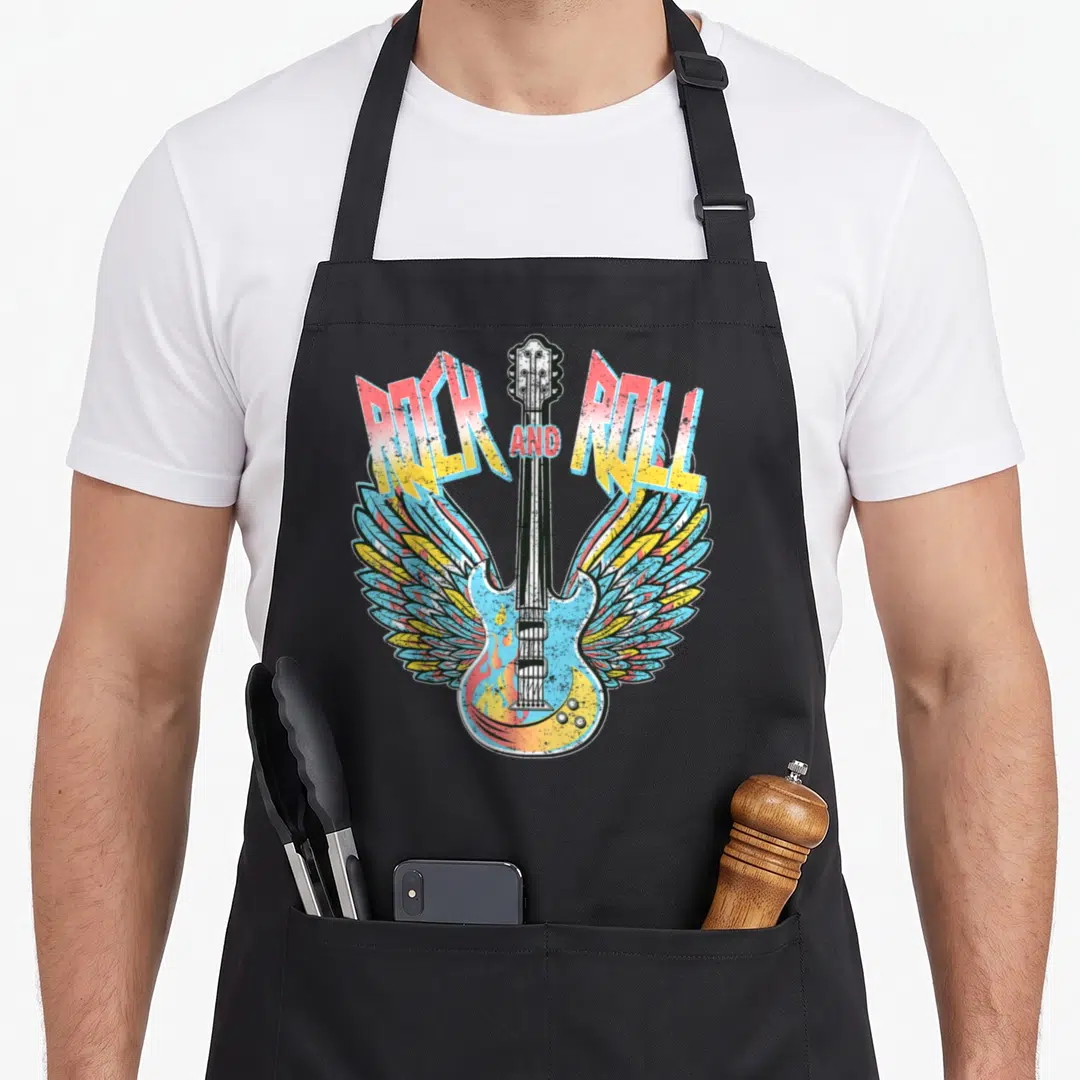 Electric 80s apron - Winged electric guitar with flames and ROCK AND ROLL text in red yellow blue black — shown on a black cotton canvas apron against a white background