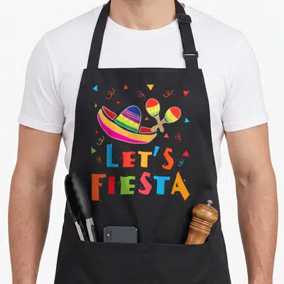 Fiesta mexico apron - Sombrero and maracas above multi-colored LET'S FIESTA text with confetti triangles — shown on a black cotton canvas apron against a white background