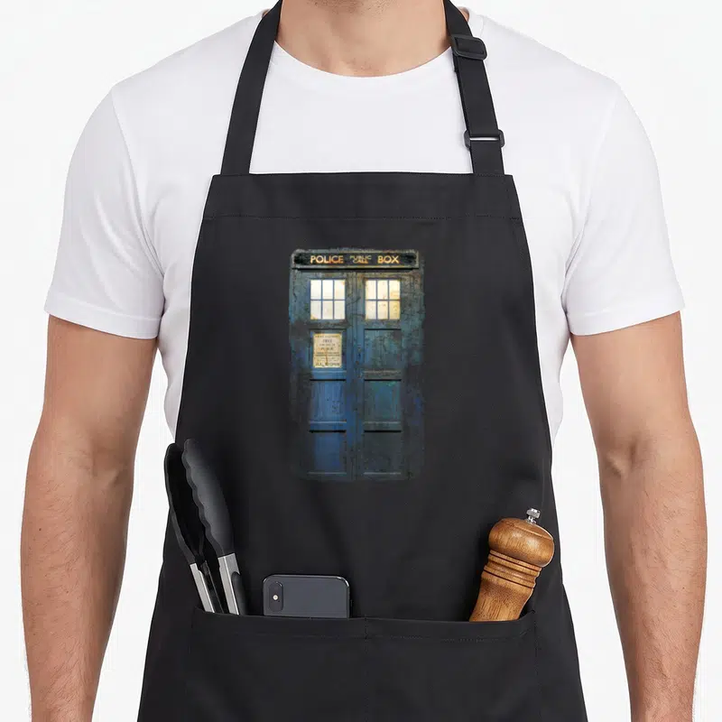 Cosplay distressed apron - Weathered blue police public box with white sign reading free for use of public — shown on a black cotton canvas apron against a white background