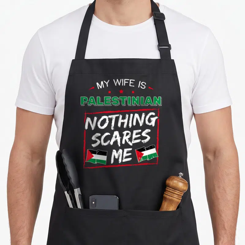 Wife palestinian apron - Stacked text reading My Wife is Palestinian Nothing Scares Me with flag fill and two corner — shown on a black cotton canvas apron against a white background