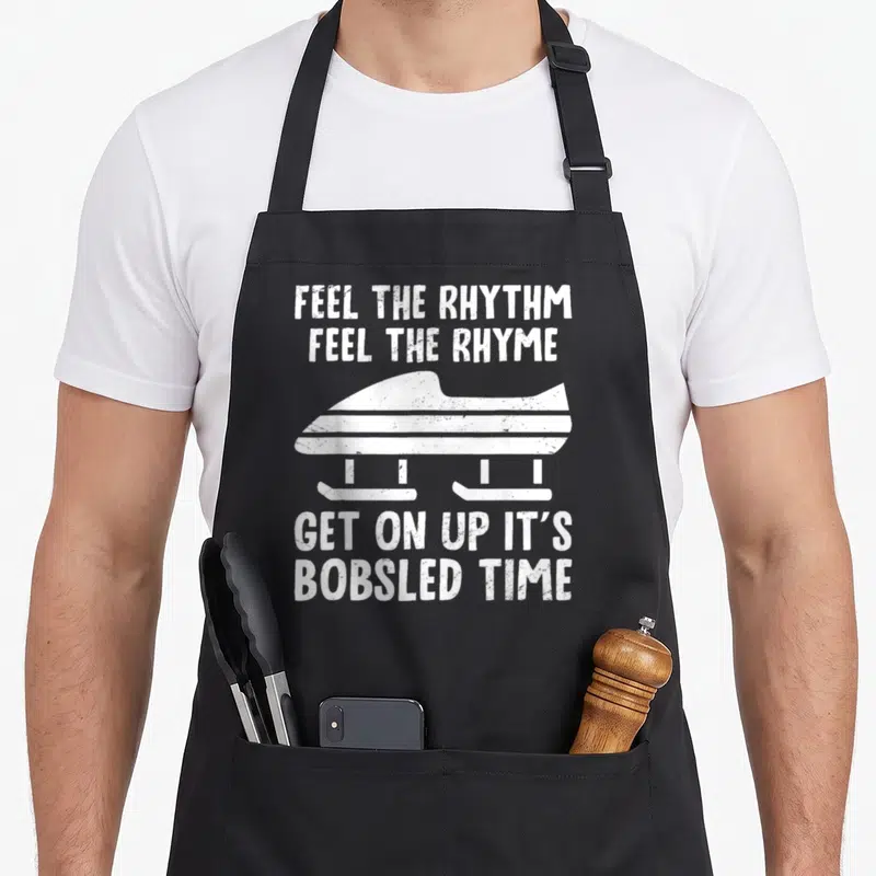 Feel bobsled apron - White distressed bobsled silhouette between text blocks reading FEEL THE RHYTHM FEEL THE RHYME GET — shown on a black cotton canvas apron against a white background