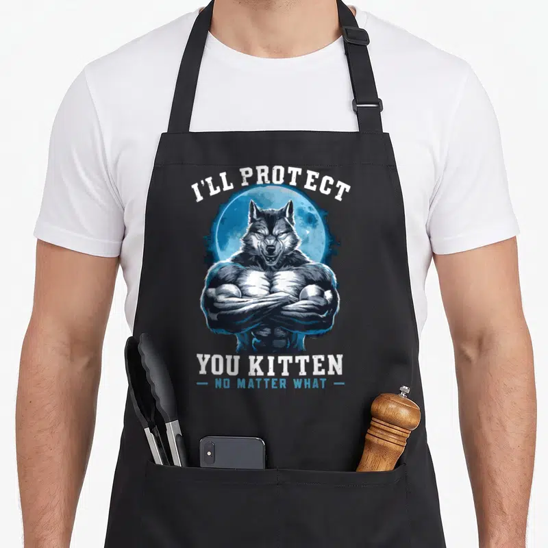 Protect alpha apron - Cartoon muscular wolf crossed arms blue moon I'll Protect You Kitten text — shown on a black cotton canvas apron against a white background