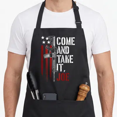 Come american flag apron - White rifle, red stripes, five stars, and Come And Take It Joe text in distressed style — shown on a black cotton canvas apron against a white background