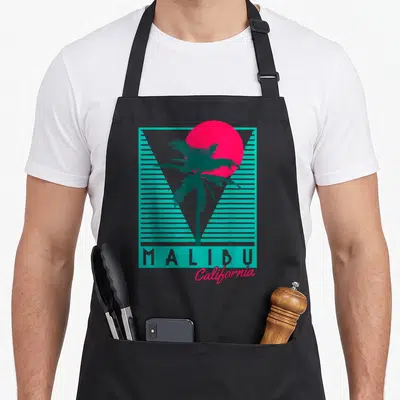 Surf tree apron - Retro teal palm tree and pink sun with MALIBU California text on black bib — shown on a black cotton canvas apron against a white background