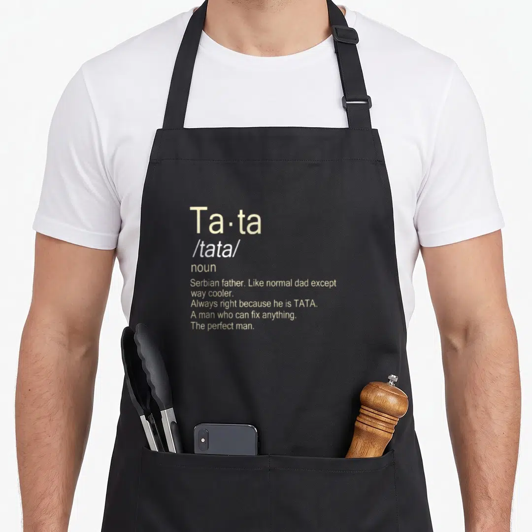 Tata serbia apron - Beige dictionary definition text reading Tata Serbian father like normal dad except way cooler — shown on a black cotton canvas apron against a white background