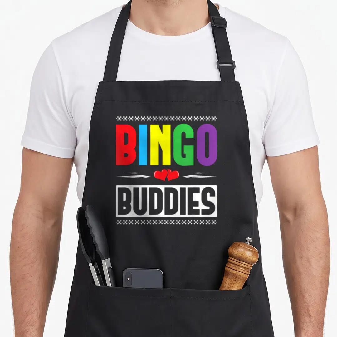 Buddy bingo apron - Rainbow BINGO BUDDIES text with two red hearts and white dotted borders — shown on a black cotton canvas apron against a white background