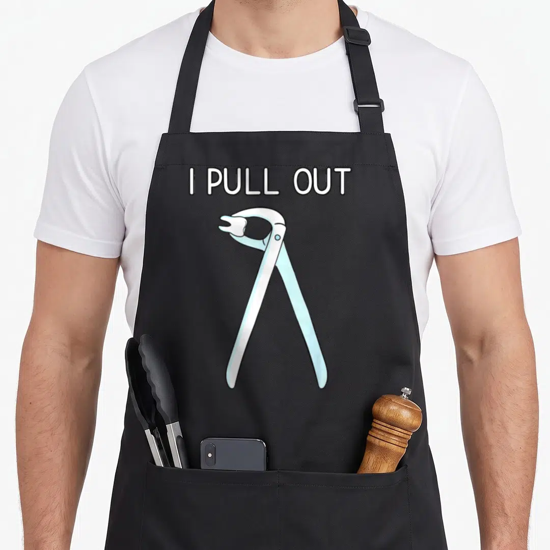 Pull dentist apron - I PULL OUT text above cartoon dental forceps holding a tooth — shown on a black cotton canvas apron against a white background