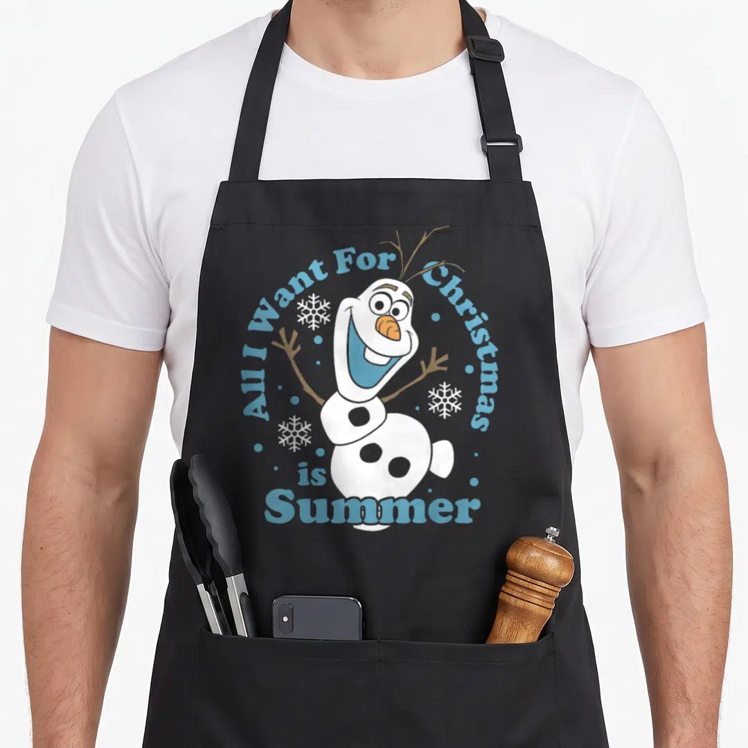 Summer christmas apron - Olaf snowman with All I Want For Christmas is Summer text and scattered snowflakes — shown on a black cotton canvas apron against a white background