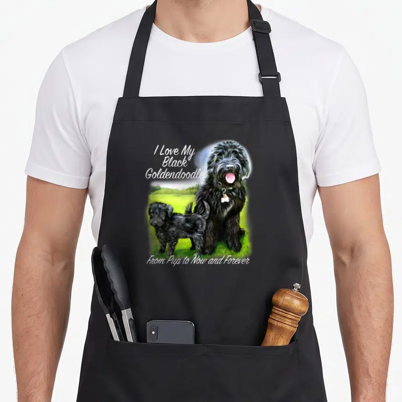 Pup goldendoodle apron - Realistic black adult dog and puppy on green grass with white text reading I Love My Black — shown on a black cotton canvas apron against a white background