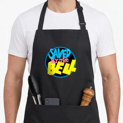 Saved bell apron - Stacked SAVED BY THE BELL text in blue pink yellow black circle — shown on a black cotton canvas apron against a white background