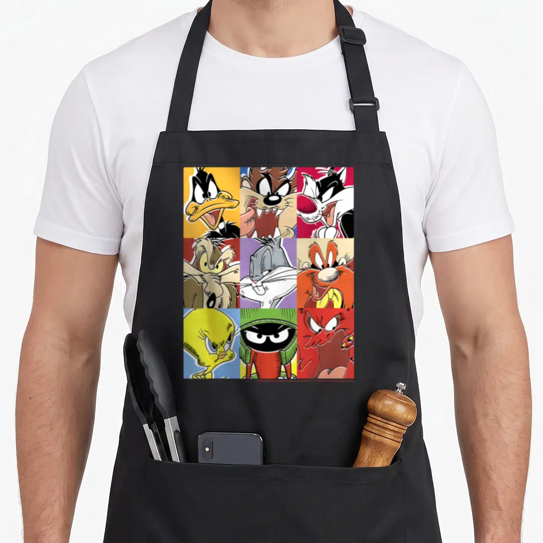 Box character aprons - Nine cartoon faces in a grid with yellow, blue, red, purple, orange backgrounds — shown on a black cotton canvas apron against a white background