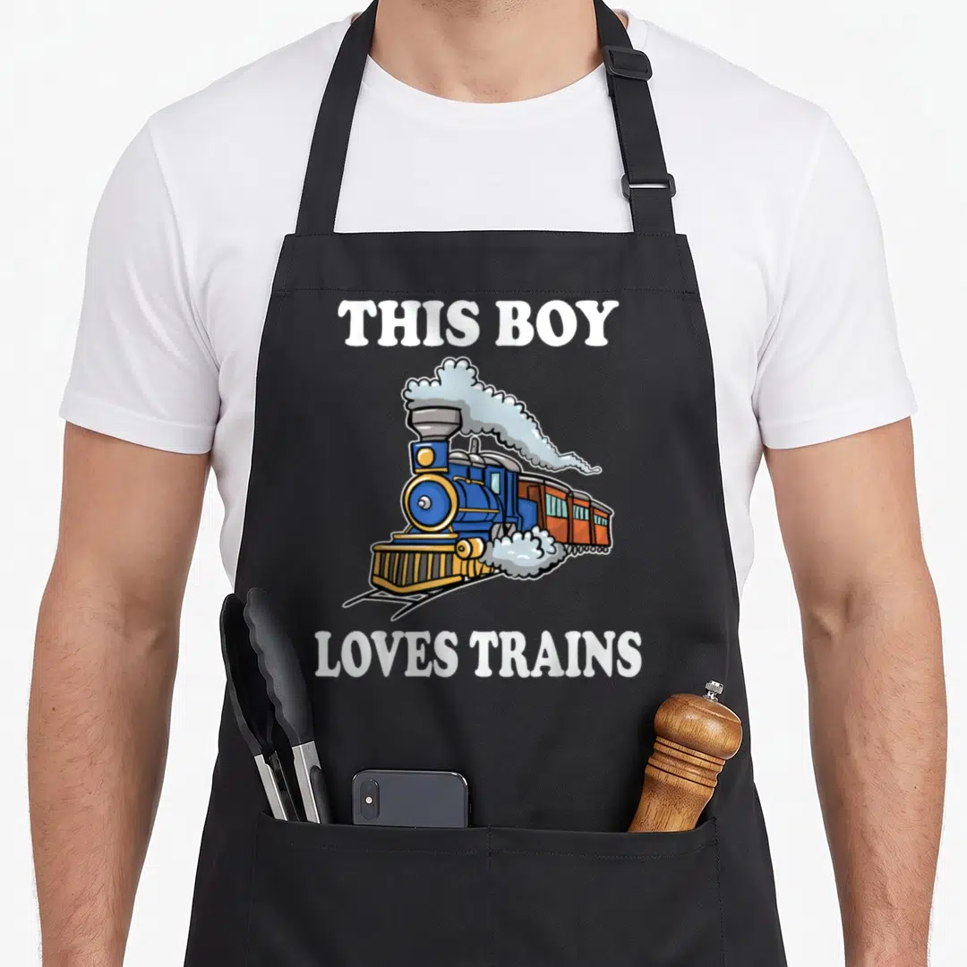Wagon boy train apron - Cartoon blue steam train with THIS BOY LOVES TRAINS text in white — shown on a black cotton canvas apron against a white background