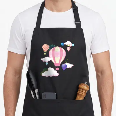 Sky balloon apron - Large pink striped hot air balloon with hearts surrounded by smaller checkered and plaid balloons — shown on a black cotton canvas apron against a white background