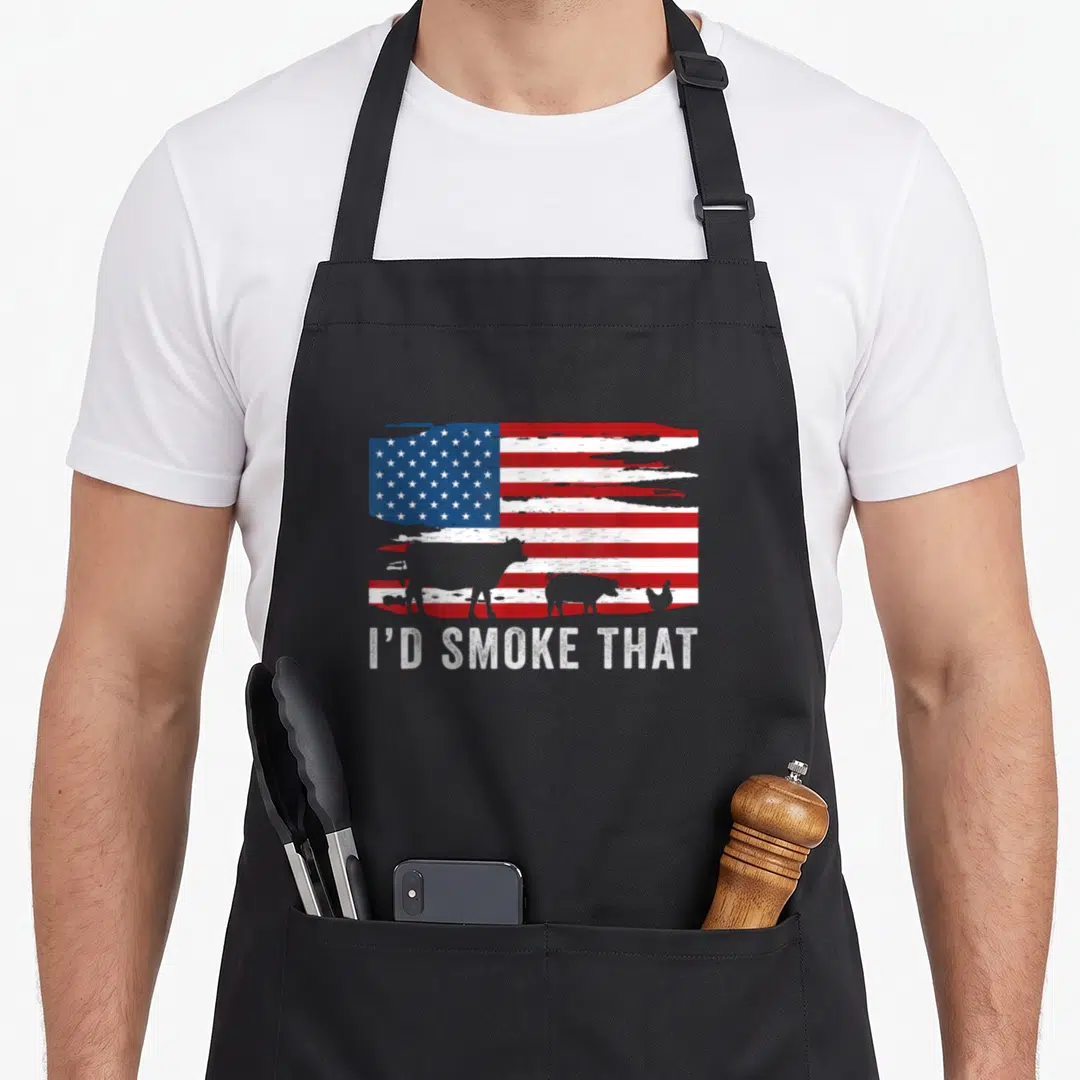 Vintage smoke barbecue apron - Distressed US flag with cow pig chicken silhouettes and I'D SMOKE THAT text — shown on a black cotton canvas apron against a white background