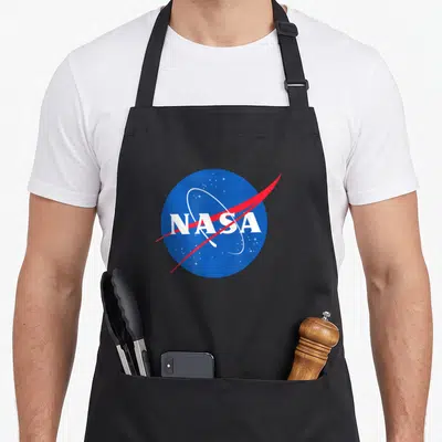 Major machine apron - Blue circle with white NASA text, red swoosh, and white stars on black background — shown on a black cotton canvas apron against a white background