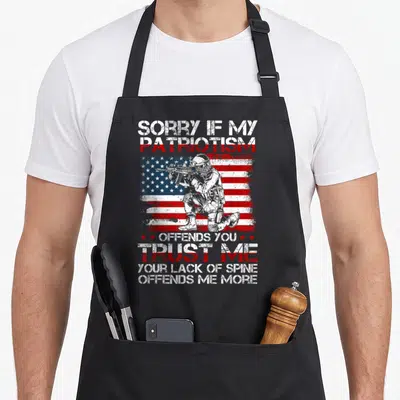 Sorry patriotic apron - Soldier holding rifle in front of distressed red white blue flag with sarcastic text — shown on a black cotton canvas apron against a white background