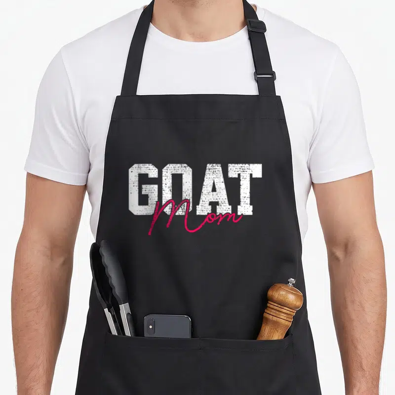 Mother farm goat aprons - White block text GOAT with pink script Mom overlapping below — shown on a black cotton canvas apron against a white background