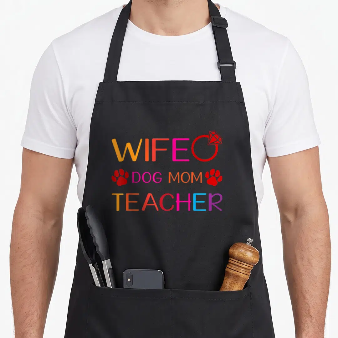 Wife dog best teacher apron - Stacked text WIFE DOG MOM TEACHER with ring and paw prints in orange pink blue purple — shown on a black cotton canvas apron against a white background
