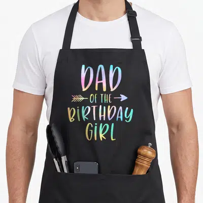 Birthday tie apron - Gradient text Dad of the Birthday Girl with arrow graphic — shown on a black cotton canvas apron against a white background