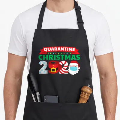 Pajama family christmas aprons - Quarantine Christmas 2020 text with toilet paper, candy cane, and masked Santa in red — shown on a black cotton canvas apron against a white background