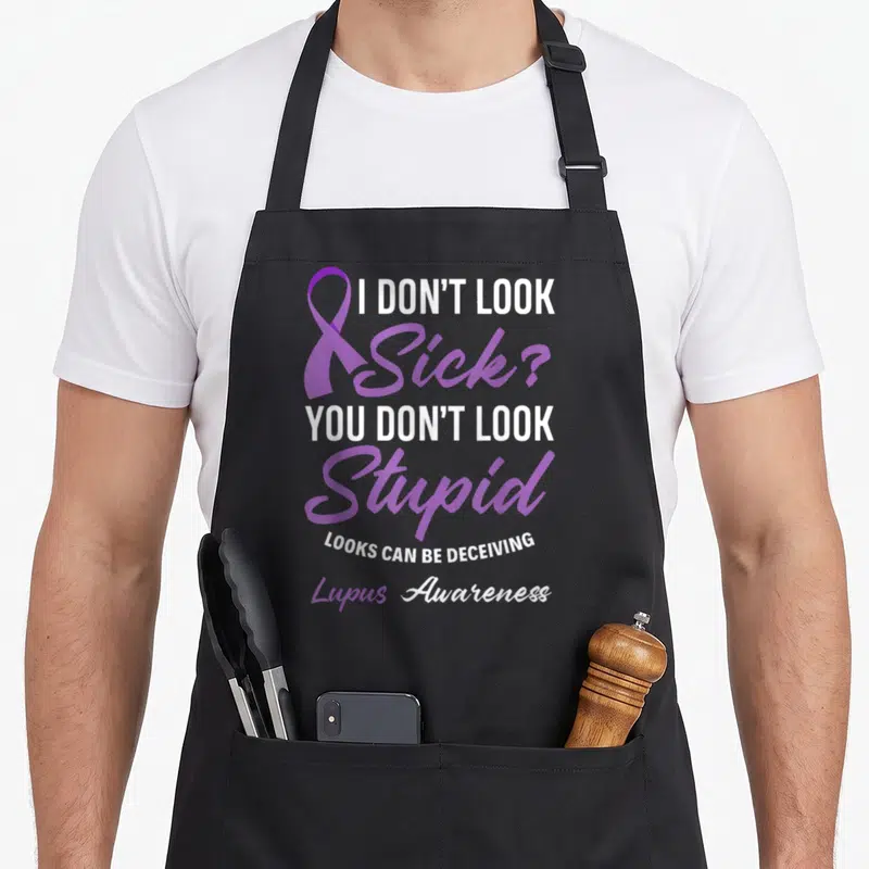 Sick stupid aprons - Purple ribbon next to stacked text reading I DON'T LOOK SICK YOU DON'T LOOK STUPID Lupus Awareness — shown on a black cotton canvas apron against a white background