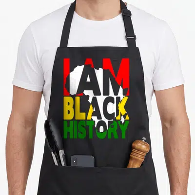 Month african american aprons - Stacked I AM BLACK HISTORY text in red yellow green over white Africa map silhouette — shown on a black cotton canvas apron against a white background