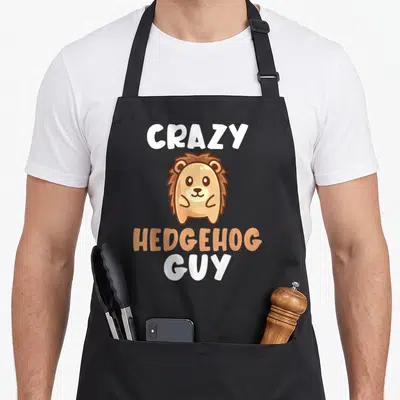Crazy hedgehog woman apron - Cartoon hedgehog in tan and brown with text Crazy Hedgehog Guy — shown on a black cotton canvas apron against a white background