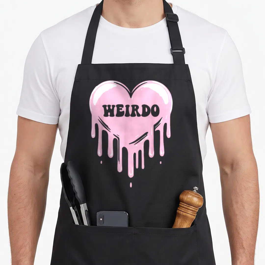 Dripping goth apron - Melting pink heart with grey WEIRDO text in cartoon style — shown on a black cotton canvas apron against a white background