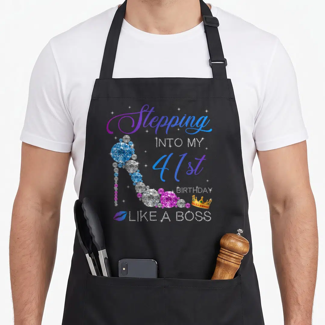 Squad bbq boss apron - Diamond high heel shoe with Stepping Into My 41st Birthday Like A Boss text and crown — shown on a black cotton canvas apron against a white background
