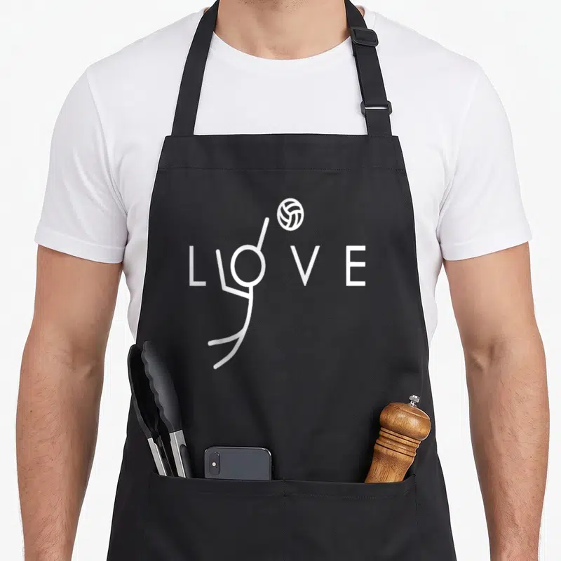 Spike volleyball apron - White LOVE text with O shaped as stick figure spiking volleyball — shown on a black cotton canvas apron against a white background