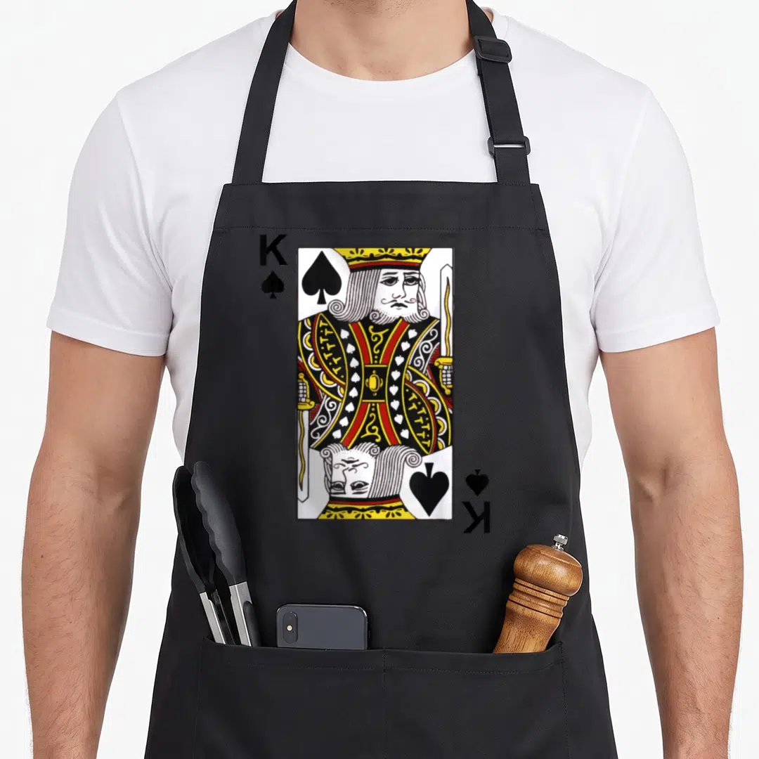 Poker king apron - Realistic King of Spades playing card with K and spade symbols in yellow, red, black, and white — shown on a black cotton canvas apron against a white background