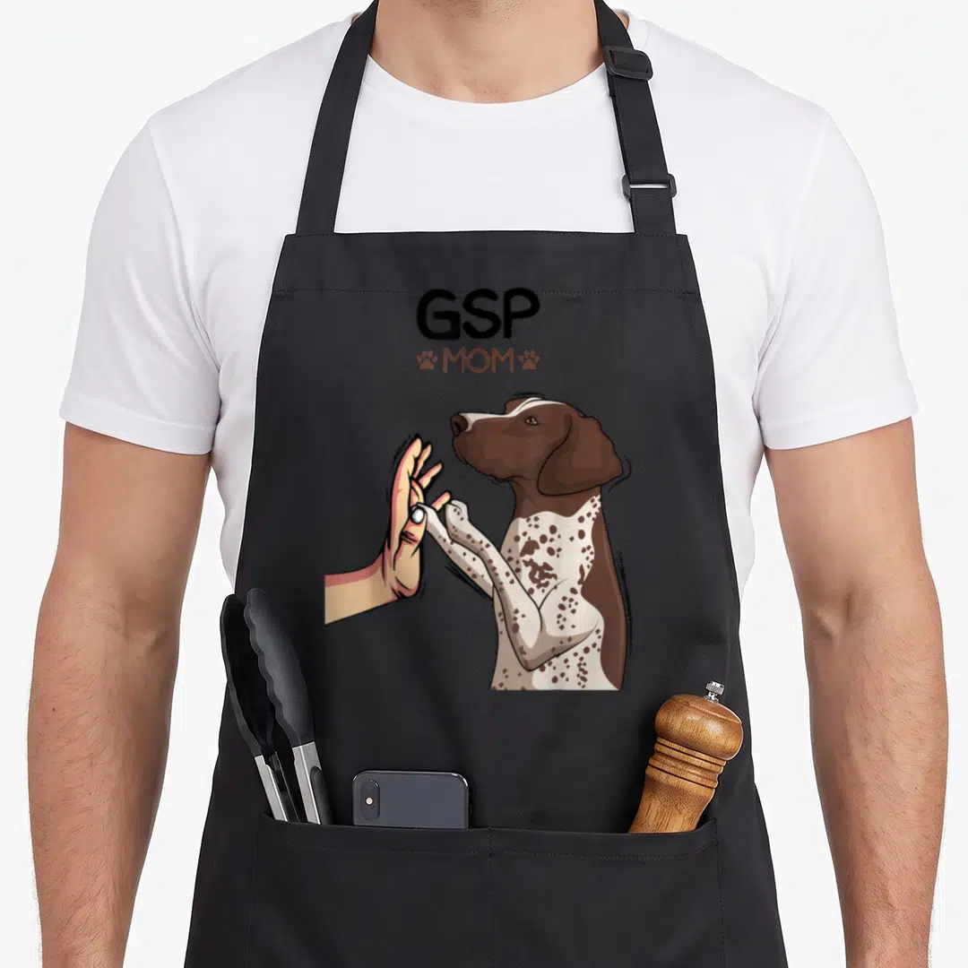 Gsp german dog apron - Cartoon GSP dog high-fiving human hand with GSP MOM text and paw prints — shown on a black cotton canvas apron against a white background