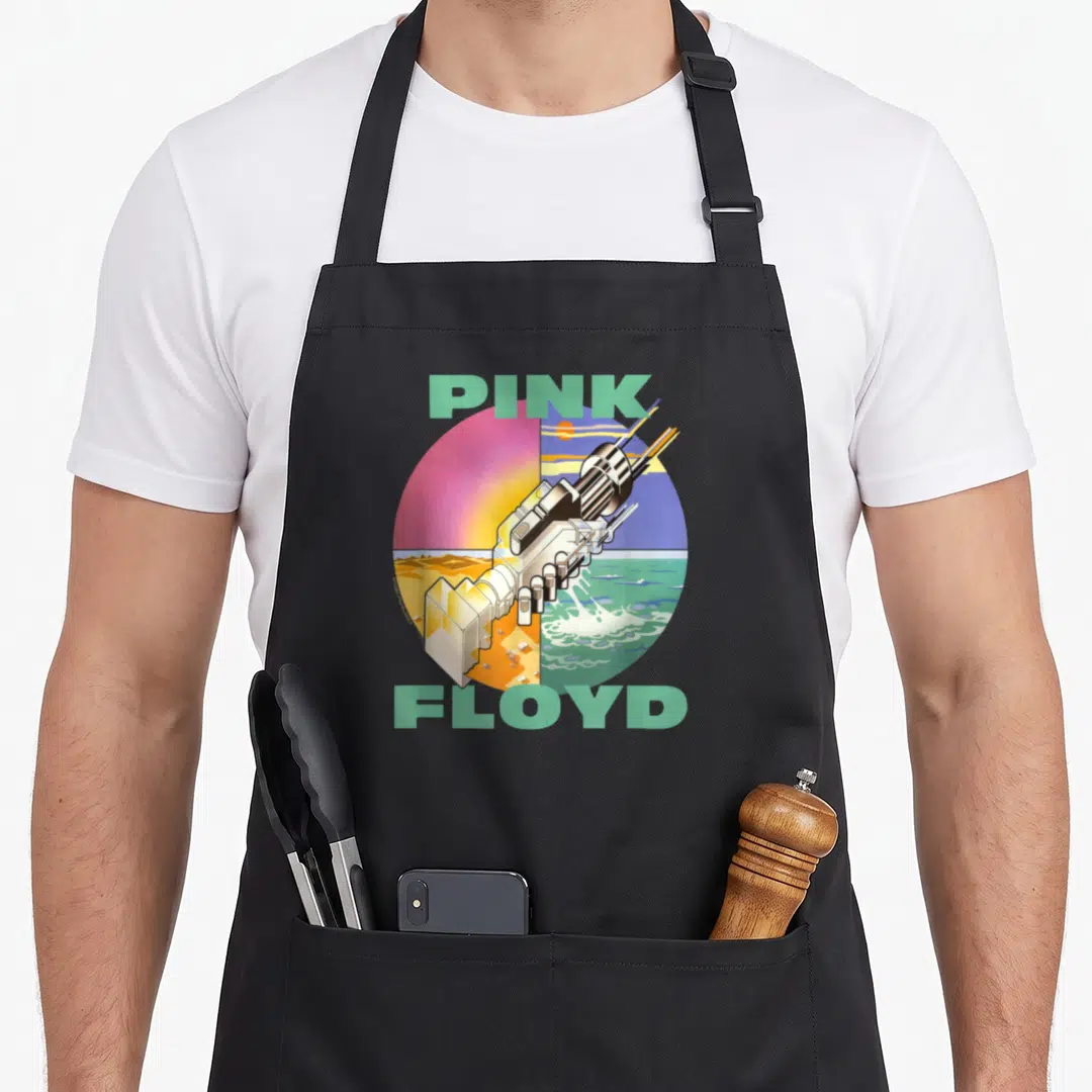 Wish progressive apron - PINK FLOYD text surrounding a surreal machine over split desert and ocean background in mint — shown on a black cotton canvas apron against a white background