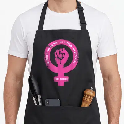 Pro business apron - Pink Venus symbol with raised fist and white text MY BODY MY CHOICE MY UTERUS MY BUSINESS — shown on a black cotton canvas apron against a white background