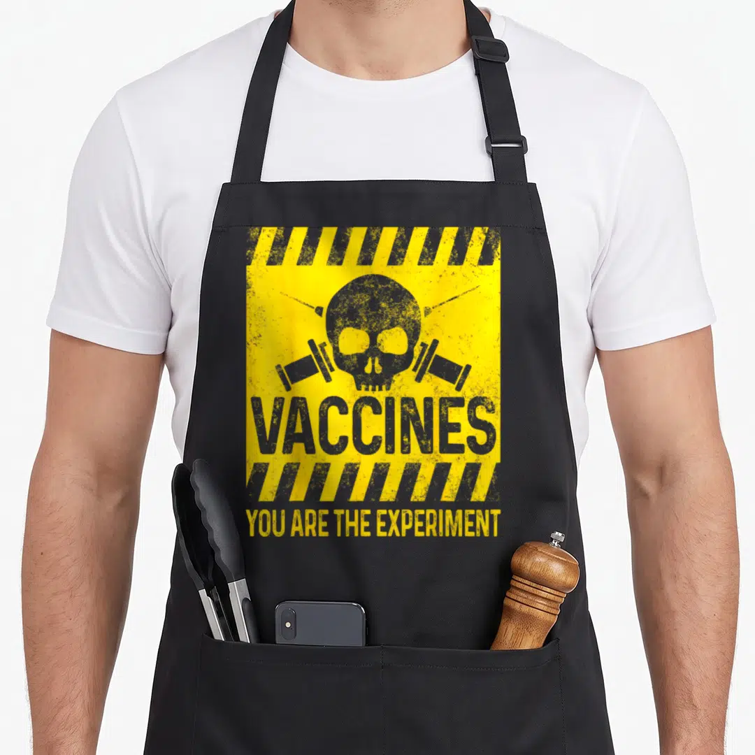 Mandatory vaccine apron - Distressed skull between two syringes with yellow and grey hazard stripes and text — shown on a black cotton canvas apron against a white background