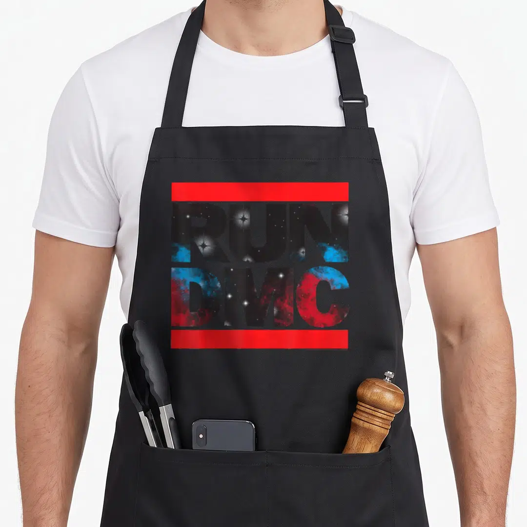 Cosmic run dmc apron - Stacked RUN DMC text filled with galaxy pattern between two red bars — shown on a black cotton canvas apron against a white background