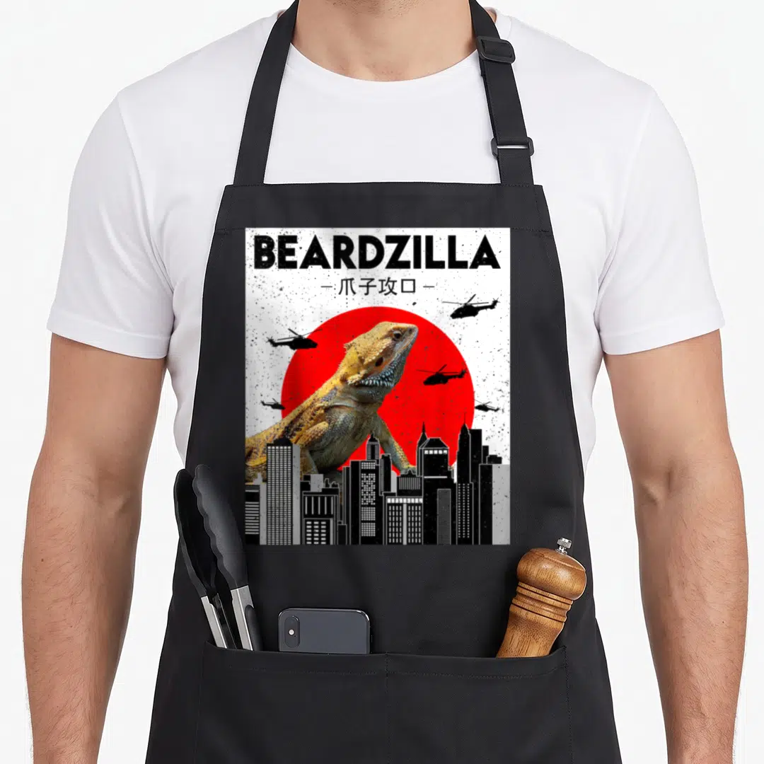 Bearded beardzilla dragon apron - Bearded dragon photo behind red sun with helicopters and city skyline and printed text — shown on a black cotton canvas apron against a white background