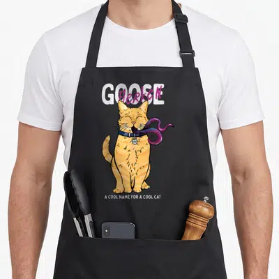 Cat goose apron - Orange cat with purple tentacles and text GOOSE Flerken A COOL NAME FOR A COOL CAT — shown on a black cotton canvas apron against a white background