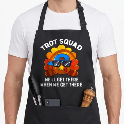 Trot thanksgiving apron - Cartoon turkey head with sunglasses and blue hat, white trot squad text and humorous quote — shown on a black cotton canvas apron against a white background