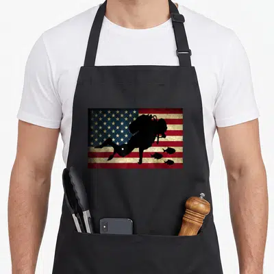 Scuba freediving apron - Black diver silhouette and three fish over distressed red white blue American flag — shown on a black cotton canvas apron against a white background
