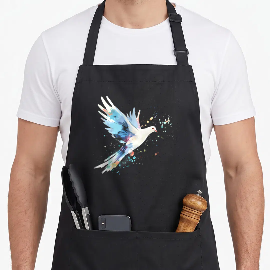 Dove watercolour bird apron - White and blue watercolor dove flying right with multicolored paint splatters — shown on a black cotton canvas apron against a white background