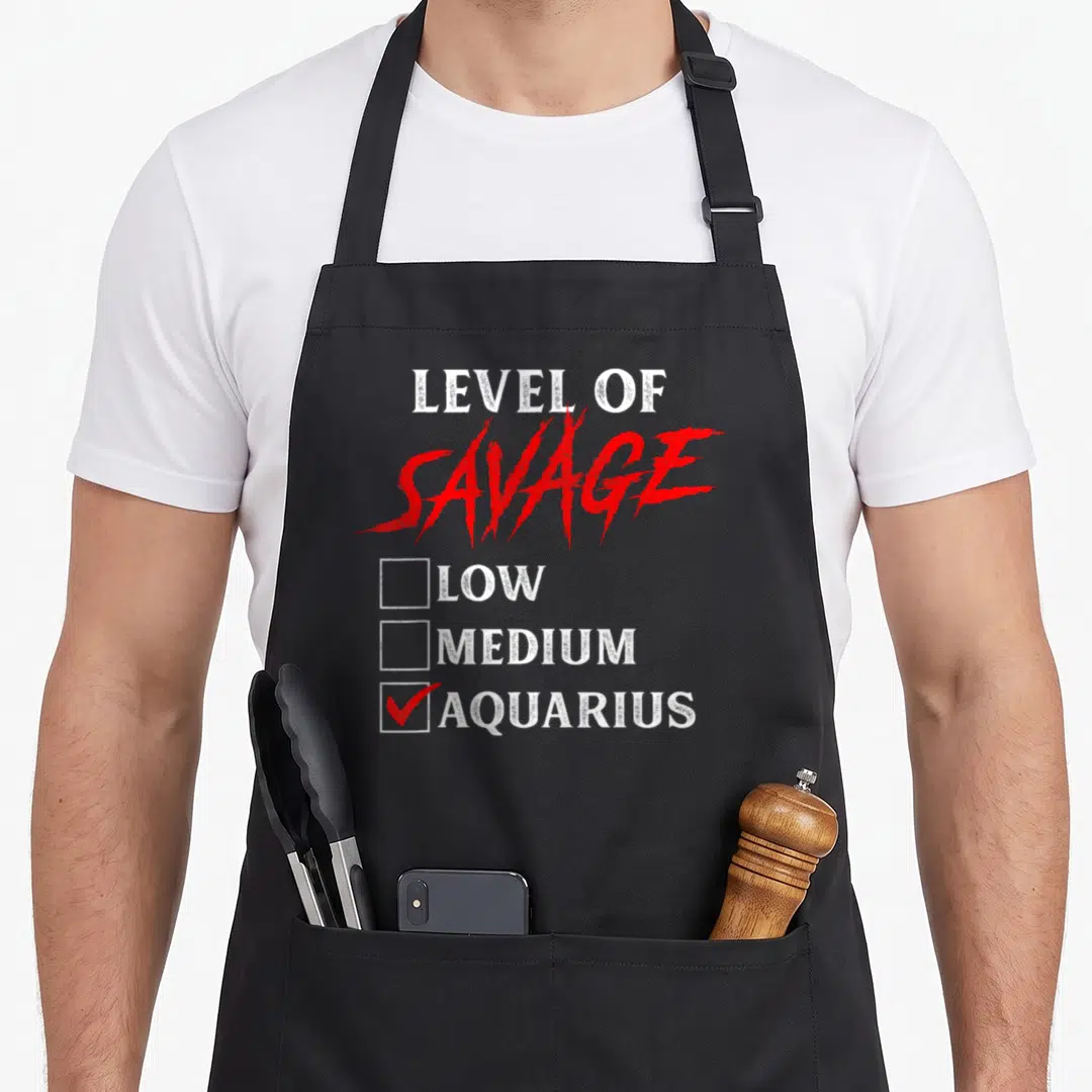 Aquarius king apron - White and red Level of Savage Aquarius checklist with checked box — shown on a black cotton canvas apron against a white background