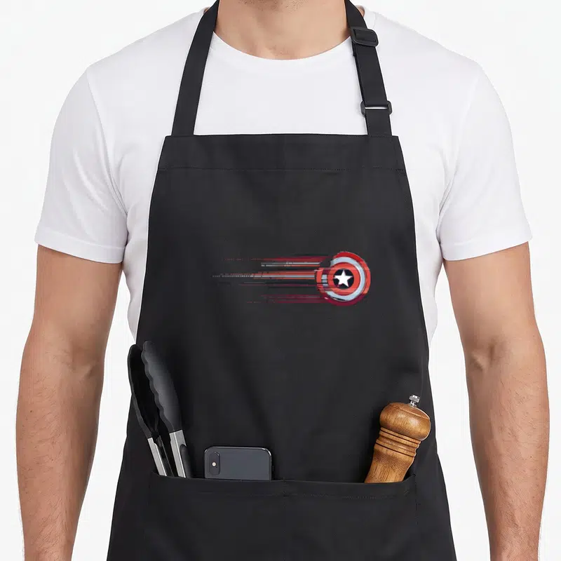 Shield stripe apron - Distressed circular shield with red white blue horizontal motion lines trailing left — shown on a black cotton canvas apron against a white background